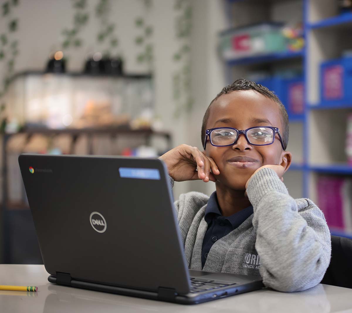 Student working on a notebook in a classroom.